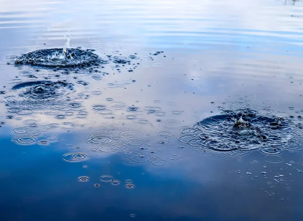 Water splashes and ripples on a water surface with a reflecting blue sky