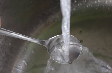 Metalik bir mutfak lavabosundaki musluktan akan su. 