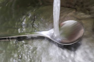 Metalik bir mutfak lavabosundaki musluktan akan su. 