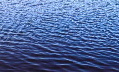 Küçük dalgalar ve güneş ışığı yansımalarıyla güzel pürüzsüz su yüzeyi dokusu