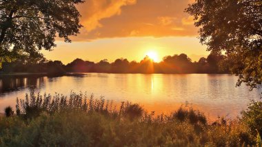 Sarı ve turuncu renkli bir gölde güzel ve romantik bir gün batımı