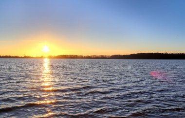 Çok güzel turuncu bir gün batımı olan gölde bir siluet.