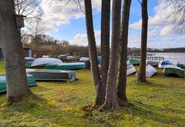 Güneşli bir günde, güzel bir gölün çimlerinde uzanan bir sürü kayık.