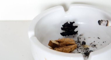 In an ashtray a burning cigarette, ashes. Rotten nut. Concept - smoking leads to lung cancer.