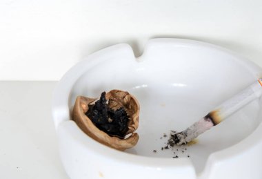 In an ashtray a burning cigarette, ashes. Rotten nut. Concept - smoking leads to lung cancer.