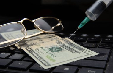 Bilgisayar klavyesinde yirmi dolarlık bir banknot var. Üzerinde gözlük ve tıbbi şırınga var. Konsept, koronovirüs salgını yüzünden ekonominin çöküşü. Hisse senetlerinin çöküşü
