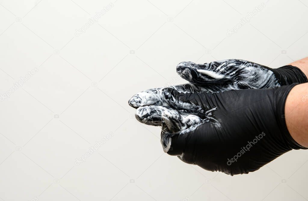 Feminine hands in black rubber gloves. In the hands of a bar of soap. Gloved soap suds. The concept is protection against coronvirus, hygiene rules. Copy space