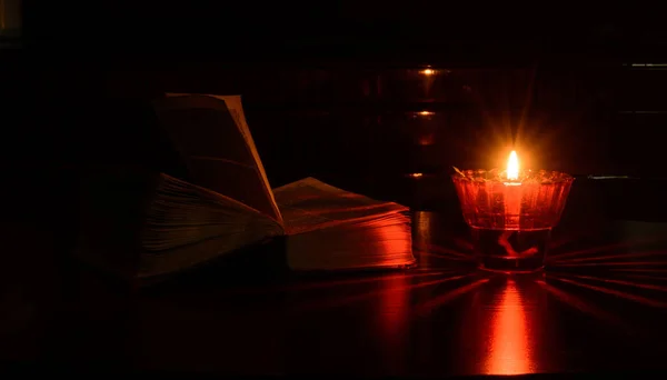 燃烧的灯立在桌子上 附近有一本打开的旧书 晚安红色的反光概念 夜间场景 — 图库照片