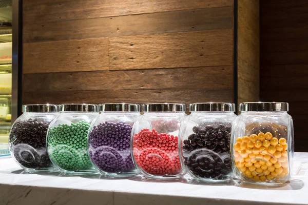 Bonbons colorés dans un pot en verre sur le comptoir — Photo