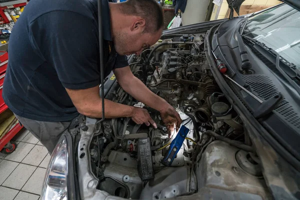Mecánico de automóviles trabajando en el motor del coche en el garaje mecánico. Servicio de reparación de coches . — Foto de Stock