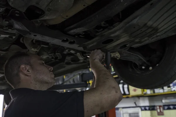 Mécanicien automobile travaillant dans un atelier mécanique. Contrôle des freins et suspensions — Photo