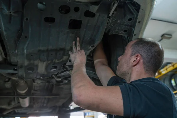 Mécanicien automobile travaillant dans un atelier mécanique. Contrôle des freins et suspensions — Photo