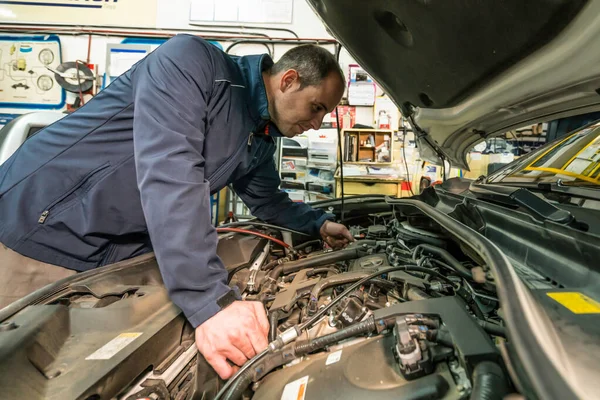 Mecánico de automóviles trabajando en el motor del coche en el garaje mecánico. Servicio de reparación de coches . — Foto de Stock