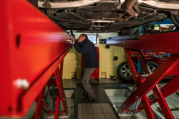 Mécanicien automobile travaillant dans un atelier mécanique. Contrôle des freins et suspensions — Photo