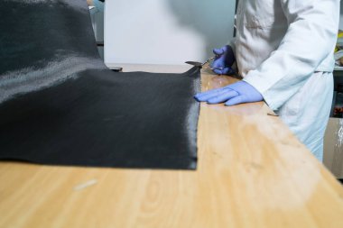 Eldivenlerle korunan ve karbon fiber kesen eller.