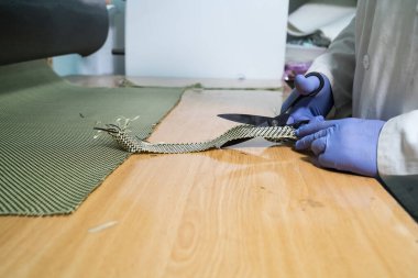 Eldivenlerle korunan ve karbon fiber kesen eller.