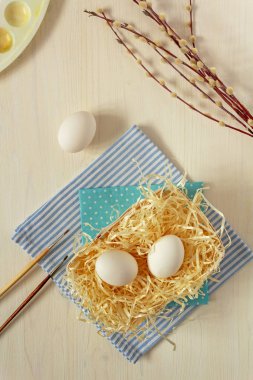 Taze, çiğ, beyaz yumurtalar ahşap bir arka planda fırçalar, paletler ve söğüt dallarıyla