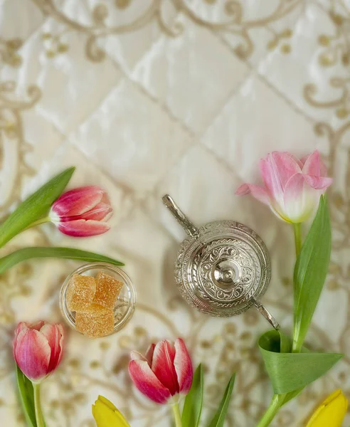Цветные тюльпаны с восточными сладостями и чайник на вышитых тканях — стоковое фото