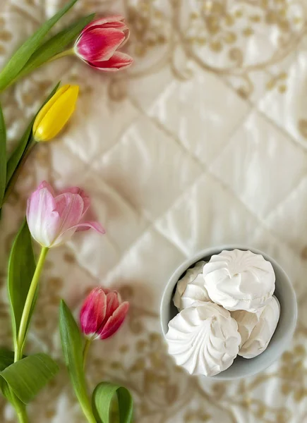 Tulipas multicoloridas com marshmallow em tecidos bordados brancos — Fotografia de Stock