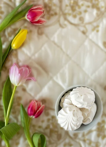 Multicolored tulips with marshmallow on white embroidered textiles