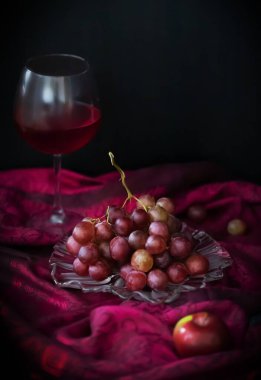 Kırmızı şarap, üzüm ve elmalarla dolu karanlık bir arka planda fotokopi alanı olan bulanık bir hayat.