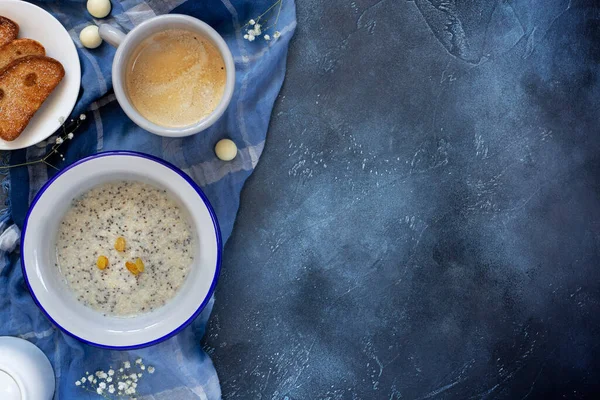 Chia tohumlu yulaf lapası ve kuru üzüm, kahve ve hamur işleri koyu mavi arka planda fotokopi alanı ile