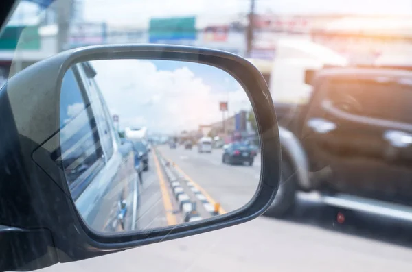 Coches corren a través de la calle desde el espejo retrovisor del coche gris — Foto de Stock