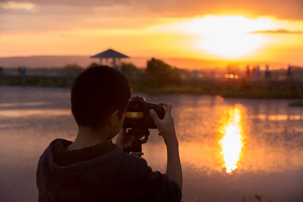 Genç fotoğrafçı ve refleks kamera gölün yanındaki tripoda., — Stok fotoğraf