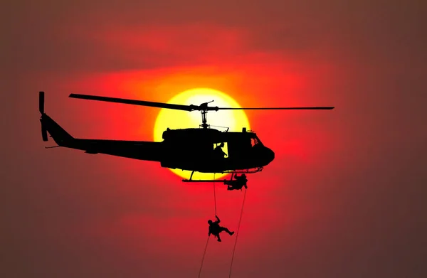 Silhouette Soldiers rappel down to attack from helicopter with w