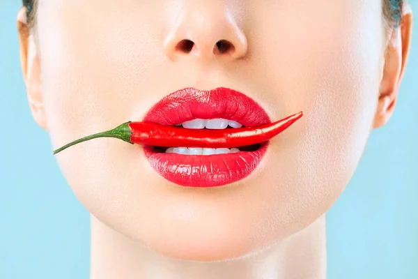 Ung kvinna med chili röd paprika isolerad en blå bakgrund. Sexiga kvinnliga läppar. Het förförisk flicka Royaltyfria Stockfoton