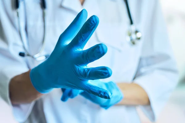 De dokter trekt rubberen handschoenen aan. geïsoleerd op een lichtblauwe achtergrond — Stockfoto