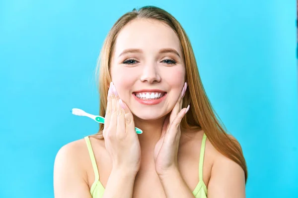 Joven hermosa mujer se dedica a la limpieza de dientes. Hermosa sonrisa dientes blancos sanos. Una chica sostiene un cepillo de dientes. El concepto de higiene bucal. Imagen promocional para una estomatología, clínica dental — Foto de Stock