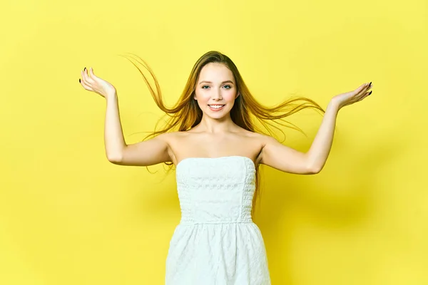 Retrato de una encantadora joven rubia, mirando a la cámara con una linda sonrisa. Estudiante chica relajante en el interior después de la universidad sobre fondo amarillo . —  Fotos de Stock