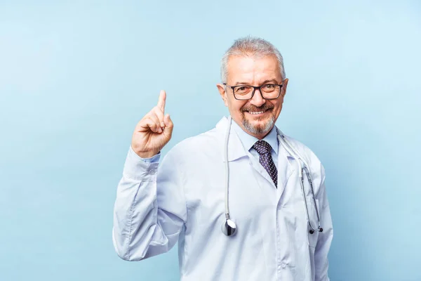 Smiling medical senior doctor with a stethoscope. On a blue background. Medic shows thumb raised up. The concept of humanitys victory over disease