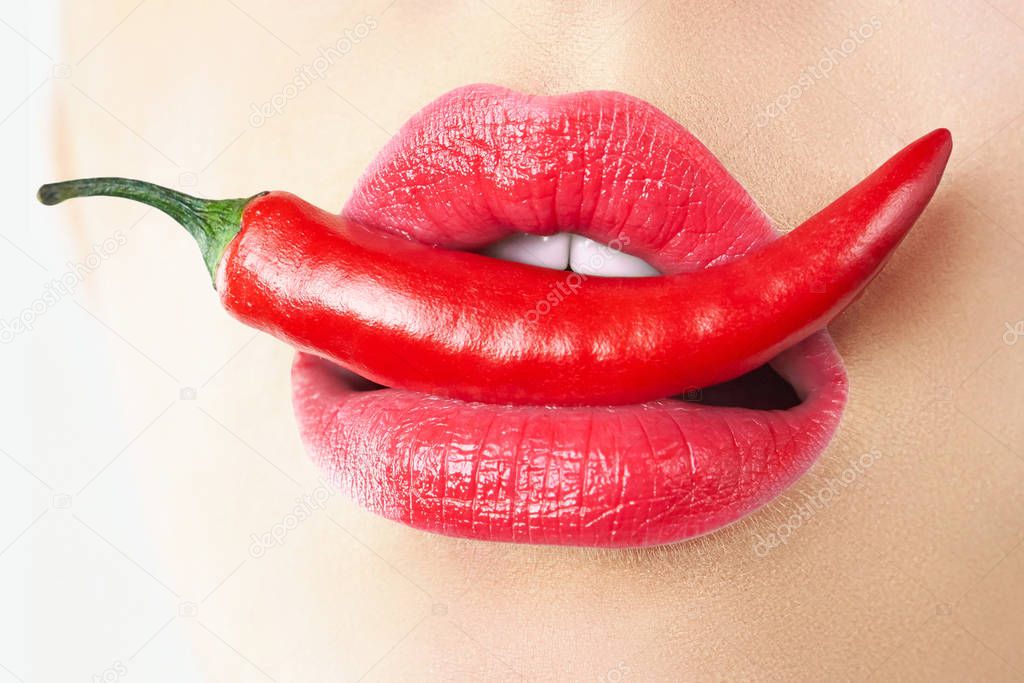 Close-up. Young woman with chili red pepper. Sexy female lips. Hot seductive girl