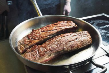 Şef restoranın mutfağında çalışıyor. Büyük bir tavada kızartılmış taze et. Restoran mutfağı geçmişi
