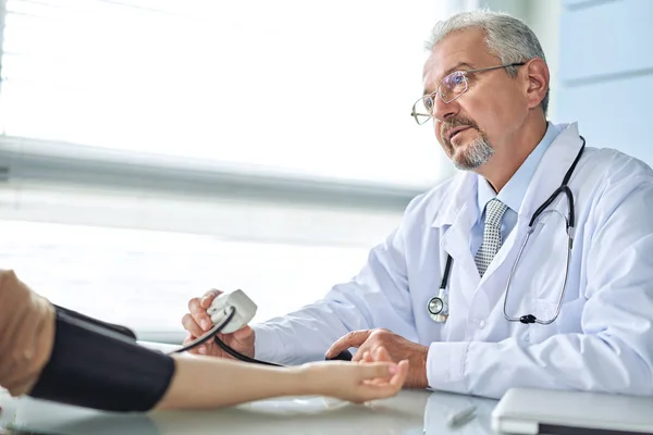 Young woman at the doctor appointment. The doctor measures the pressure of the patient — Stock Photo, Image