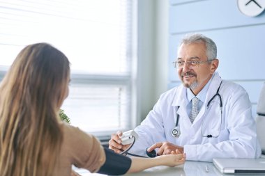 Doktor randevusundaki genç kadın. Doktor hastanın basıncını ölçer.