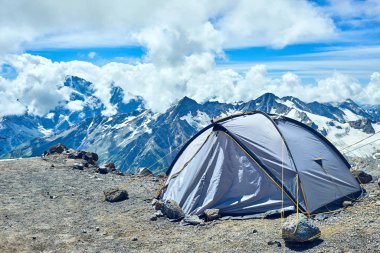 Dağlardaki turist çadırı Elbrus, karlı zirvelerin arka planına karşı