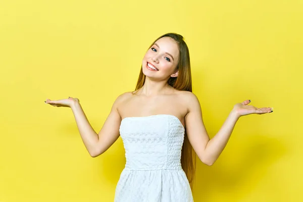 Portret van een vrolijke jongedame die glimlacht en uw product presenteert. Vrouw wijst naar copyspace. Geïsoleerd op een gele achtergrond. — Stockfoto