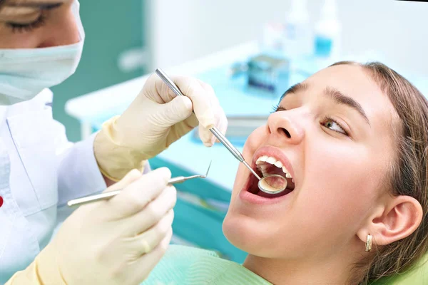 Girl sitting at dental chair with open mouth during oral check up while doctor. Visiting dentist office. Dentistry concept. — 图库照片