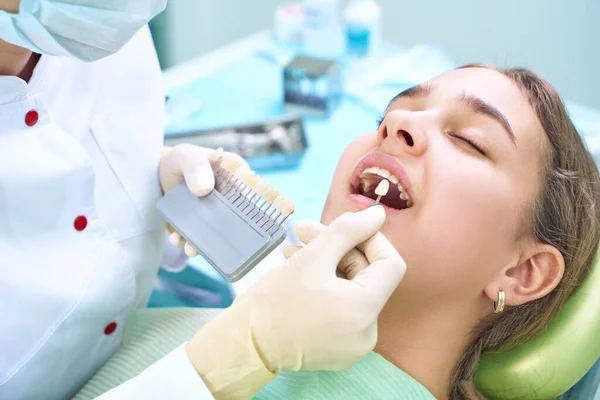 Beautiful smile and white teeth of a young woman. Matching the shades of the implants or the process of teeth whitening. Teeth palette. — Stockfoto