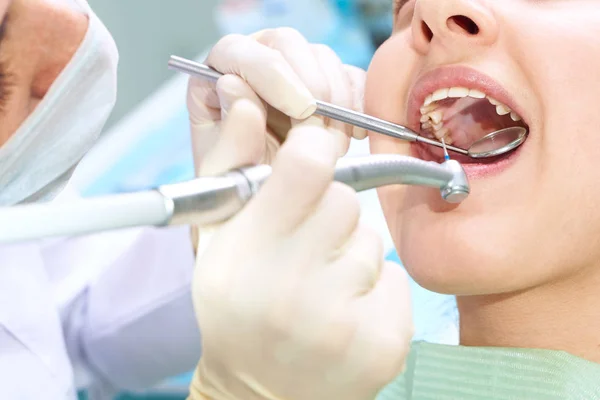 Girl sitting at dental chair with open mouth during oral check up while doctor. Visiting dentist office. Dentistry concept.