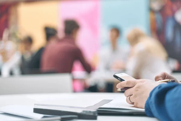 Zakelijke persoon met een moderne smartphone en aanraken op een leeg scherm. Stijlvolle moderne kantoorwerkplek op een achtergrond. — Stockfoto