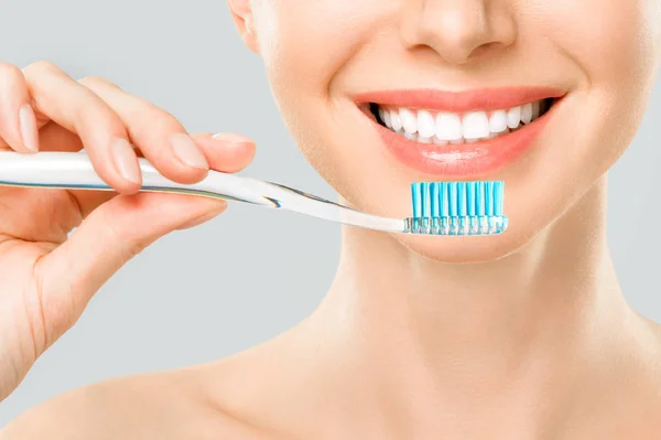 Mooie lachende vrouw die haar tanden schoonmaakt met een tandenborstel in een tandhygiëne concept. geïsoleerd op wit — Stockfoto