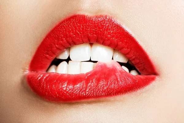 Primer plano de los dientes blancos de una mujer que se muerde los labios — Foto de Stock