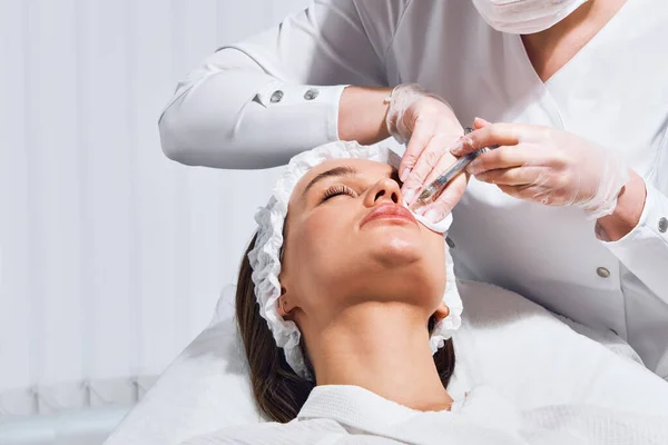 Procedimiento de corrección de forma de labio en un salón de cosmetología. El especialista realiza una inyección en los labios del paciente. Aumento de labios — Foto de Stock