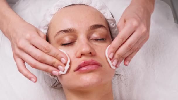 Limpie con cara de servilleta estéril. Mujer bonita joven recibiendo tratamientos en salones de belleza. Espuma de limpieza facial usando . — Vídeos de Stock