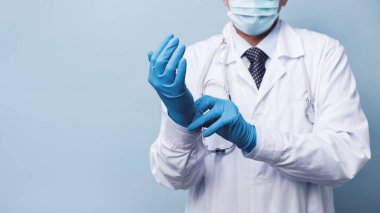 Tıbbi maskeli bir erkek doktor lastik eldiven giyer. Enfeksiyon ve koronovirüs için ilaçlar