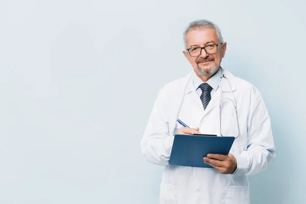 Oudere man met baard arts in wit uniform met een stethoscoop met een blauwe map. Doctor op de achtergrond van een medisch onderzoekslaboratorium. — Stockfoto